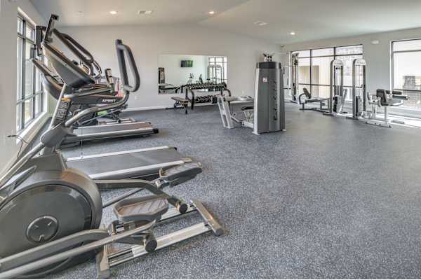 a gym with cardio equipment and weights on the floor